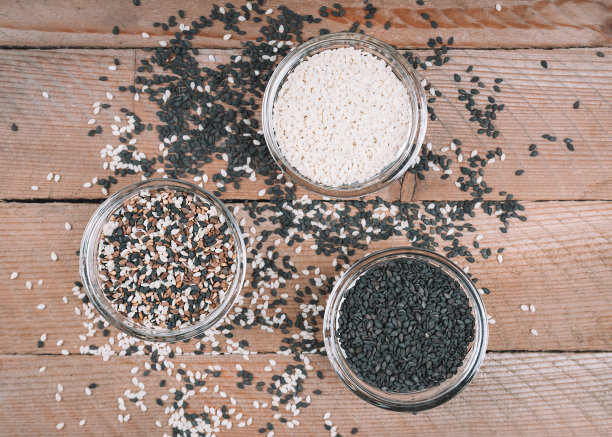 不同种类的芝麻。白、黑、多色芝麻。木质背景上的调味料。图片下载