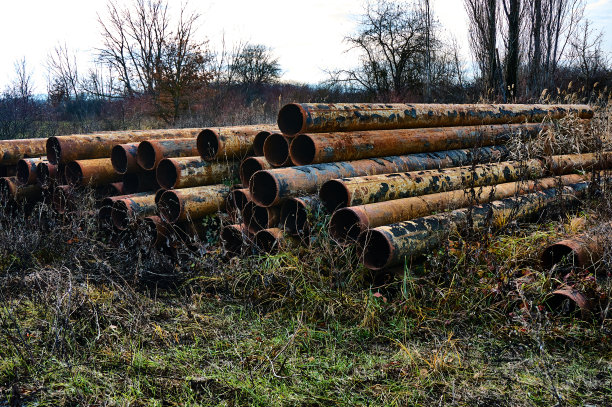 锈迹斑斑的管道散落在现有电线支撑物附近的草丛中。图片下载