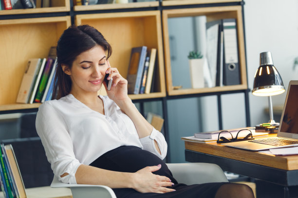 在办公室工作的怀孕的商业女性母亲坐在电话里聊天图片下载