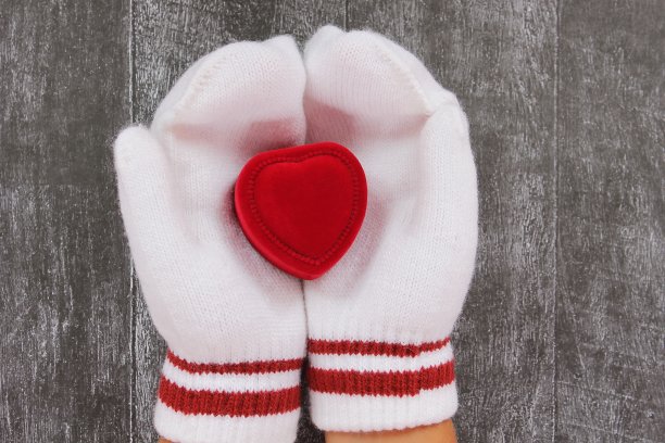 双手戴着连指手套，拿着一个心形的天鹅绒红色小盒子图片下载