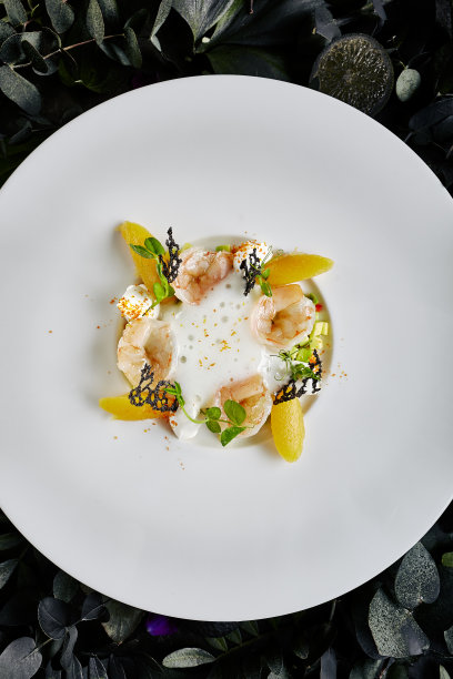 精致的餐厅餐盘虎虾与鳄梨鞑靼和甜辣椒下的泡沫酸橙汁俯视图。大虾在深色的叶子和花的背景微距照片图片下载