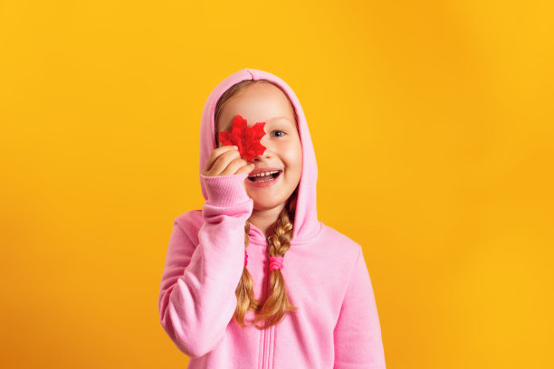 一个快乐的小女孩，黄色的背景上是秋红的枫叶图片下载