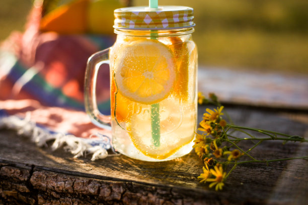 夏天的饮料在罐子和篮子与夏天的水果在阳光下，户外野餐或派对的概念图片下载