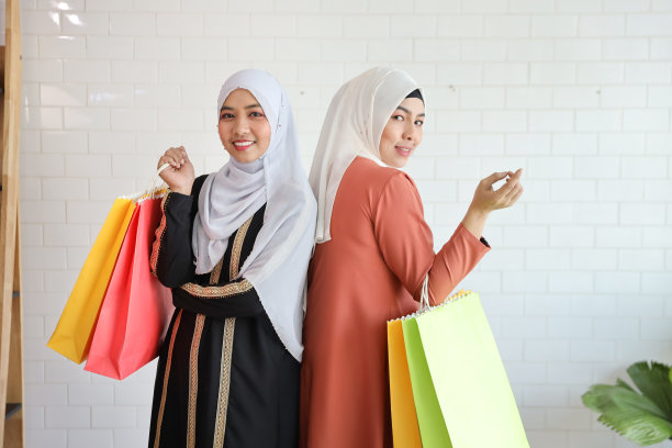 在购物中心站立并拿着购物袋的年轻穆斯林女孩图片下载