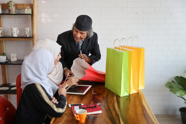 穆斯林商人向年轻的阿拉伯女顾客递购物袋图片下载