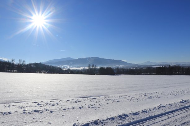 从捷克共和国贝斯基山脉最高的山莱沙霍拉的多布拉蒂奇村观看。蔚蓝的天空和白色的太阳。很冷的天气。田野上覆盖着奇妙的积雪图片下载