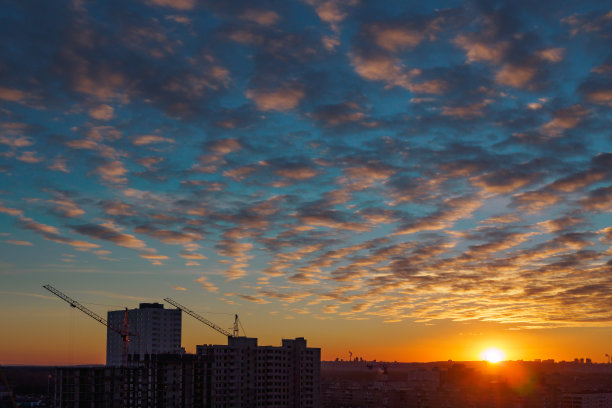 城市景观与日落和卷云。正在施工的建筑和起重机的观点图片下载