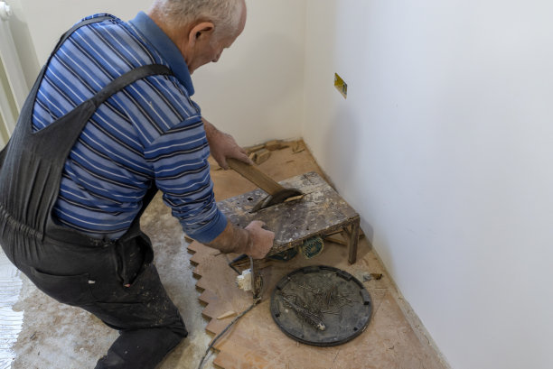 高级拼花工人正在用锯子切割地板图片下载
