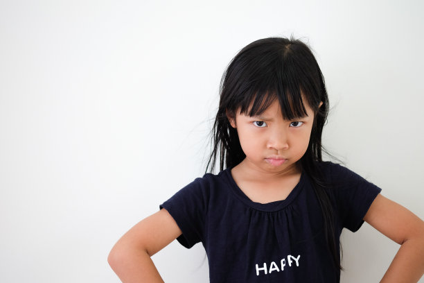 在白色背景下，亚洲女孩脸上露出愤怒的表情，手臂放在臀部图片下载