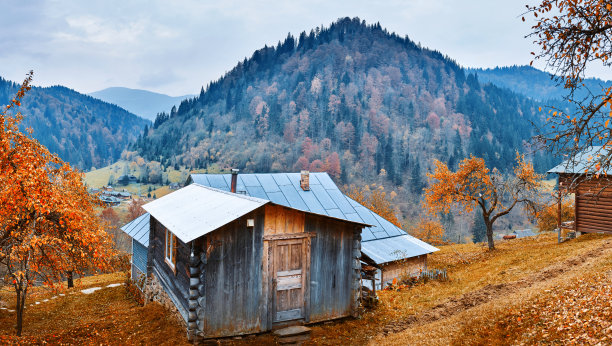 美丽的秋季山景与山坡上的木屋，和戏剧性的多云天空在傍晚的山上图片下载
