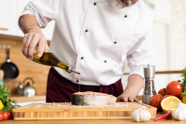 厨师准备新鲜的鲑鱼、鳟鱼，撒上海盐和蔬菜。水平的照片。概念烹饪健康素食菜肴，清洁食品，餐饮，酒店业务。图片下载