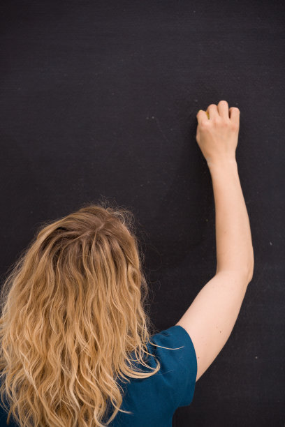 小女孩在黑色背景上画画。商业女性在黑板上写字。老师在黑板上手绘。教育与观念观念。图片下载