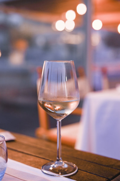 餐厅桌子上的一杯白葡萄酒。健美的照片。眩光和光点。文本的空闲空间。图片下载