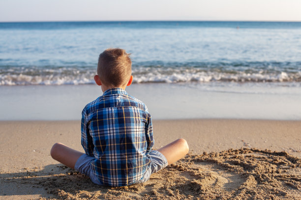 坐在海滩上沉思的男孩图片下载