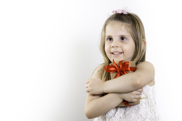 可爱的女孩，女孩拿着礼物与红色的蝴蝶结在儿童节。白色背景，拷贝空间图片下载