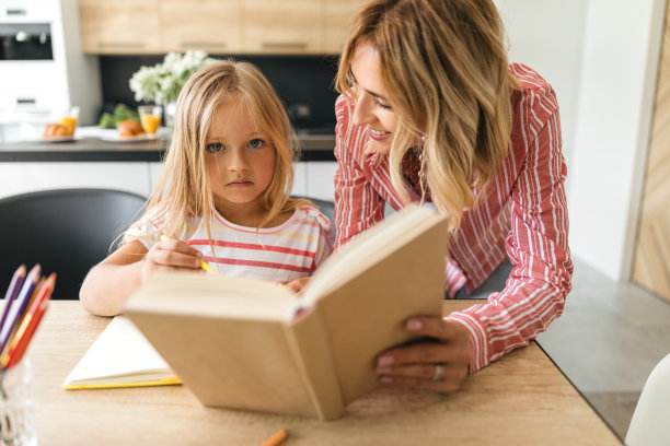 悲伤的女孩与微笑的妈妈做作业的库存照片图片下载