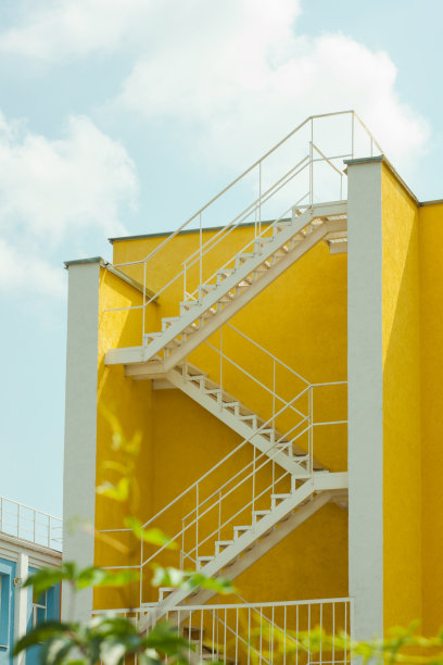 现代黄色和白色的房子与金属之字形楼梯。庭院建筑，美化。图片下载
