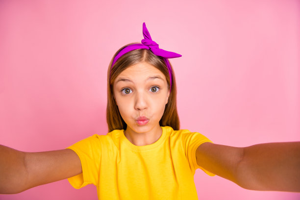 她的自画像，她很好，有吸引力，可爱的，愉快的，愉快的十岁前的女孩穿着黄色的t恤，愚弄有乐趣的自由时间送你的吻孤立在粉红色的背景图片下载