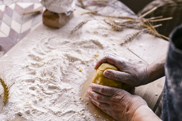 女性的手和面团。一个妇女正在为家庭烘焙准备面团。乡村风格的照片。木桌和面粉。文本的空闲空间。图片下载