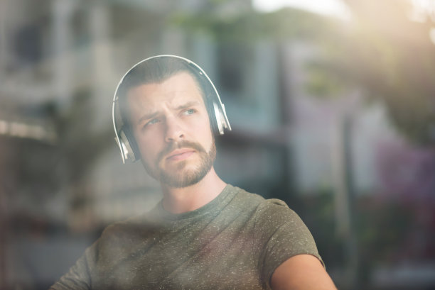 大胡子男人戴着耳机听音乐的肖像。图片下载