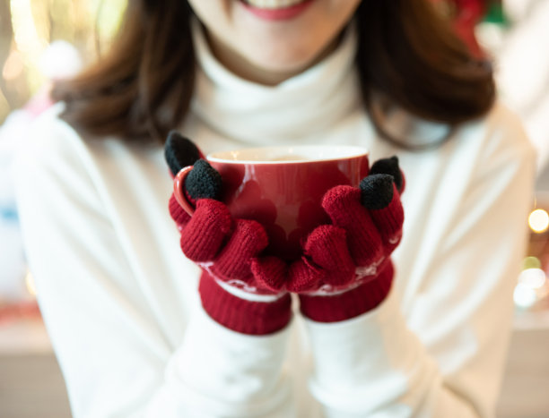 亚洲女人穿着白色的衣服和红色的手套拿着一杯咖啡。图片下载