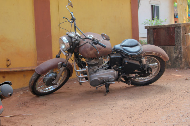 旧的生锈的摩托车上面橙色的墙图片下载