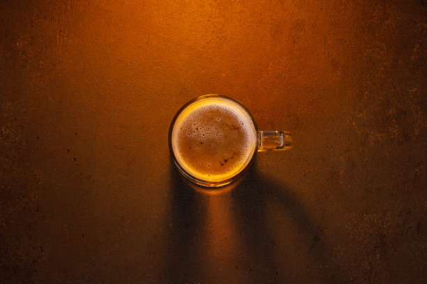 棕色有纹理的桌子上放着啤酒杯图片下载