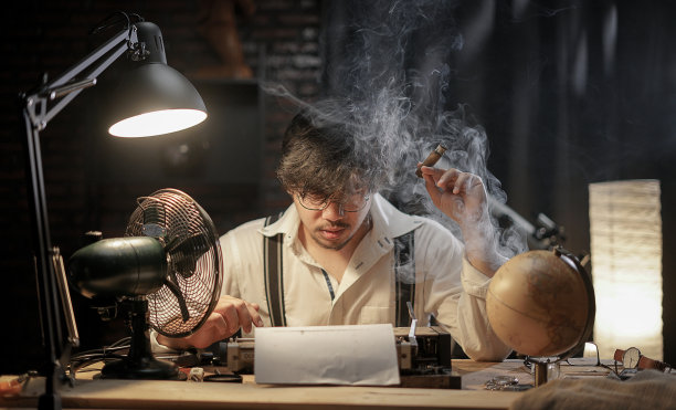 压力山大的男人抽雪茄寻找打字工作的灵感。50年代的场景设置。图片下载