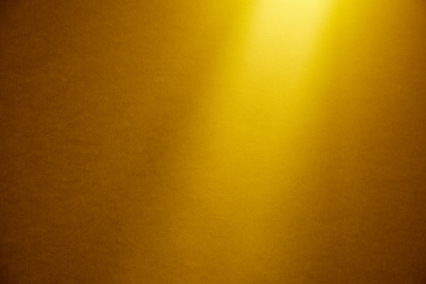 一束浅黄色的光从一个深黄色的精细纹理的背景上方照亮。图片下载