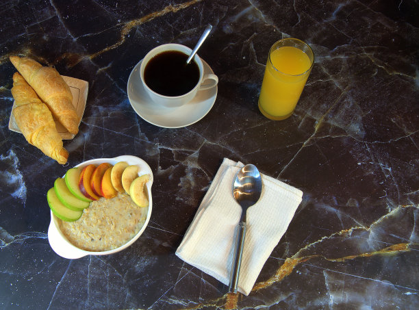 传统的早餐，燕麦片水果片，一杯黑咖啡，两个羊角面包和一杯橙汁。-图片下载