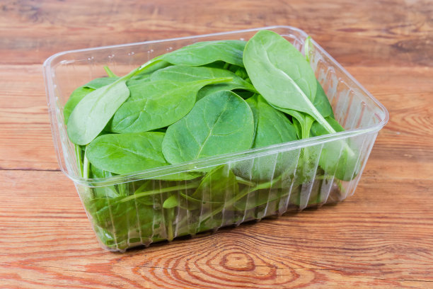 新鲜的菠菜叶装在塑料容器里放在质朴的桌子上图片下载