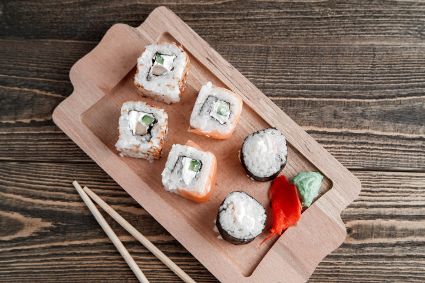 三种不同的日式卷，佐以芥末和生姜，放在竹制托盘上，背景是美丽的木头图片下载