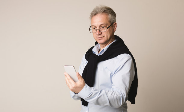 高级商人在智能手机上输入信息，灰色背景图片下载