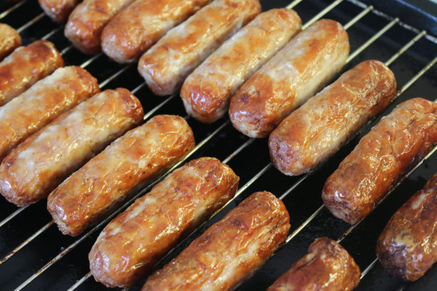 这是一幅在厨房烤架下用不锈钢烧烤架烤的烤牛肉和猪肉香肠的图片，烤得油腻的烤香肠比在煎锅里烤的更健康图片下载