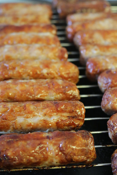 这是一幅在厨房烤架下用不锈钢烧烤架烤的烤牛肉和猪肉香肠的图片，烤得油腻的烤香肠比在煎锅里烤的更健康图片下载