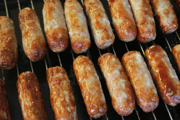 这是一幅在厨房烤架下用不锈钢烧烤架烤的烤牛肉和猪肉香肠的图片，烤得油腻的烤香肠比在煎锅里烤的更健康图片下载