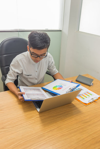 垂直照片的亚洲商人阅读文件图片下载