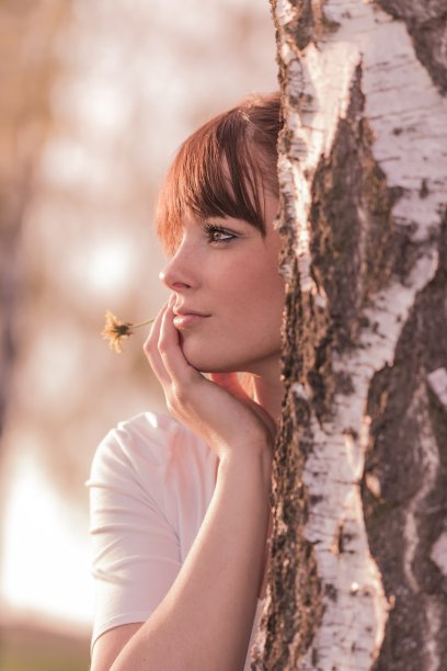 美丽的女孩带着花在树干上幻想着大自然图片下载