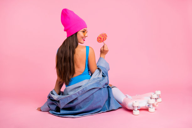 背面背面照片迷人的女士戴眼镜，戴着糖果，穿着蓝色泳衣帽袜子隔离在粉红色的背景图片下载