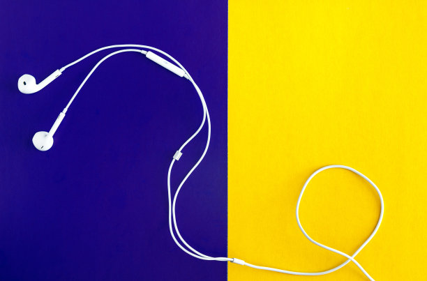 黄紫罗兰背景的白色耳机。从以上观点。图片下载