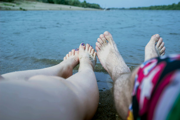 脚边的情侣，在河边，享受着海滩假日，嗡嗡和放松图片下载