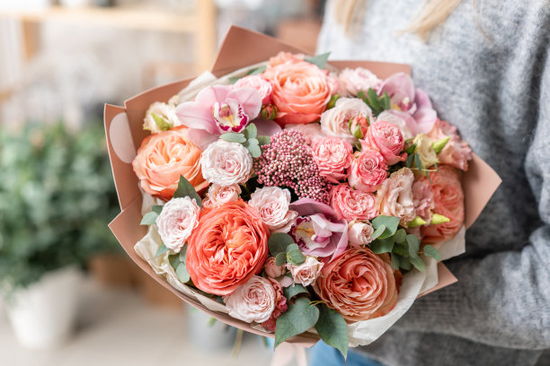 美丽的新鲜切花束混合在女人的手。花店花匠的工作。柔和的色调颜色素材图片