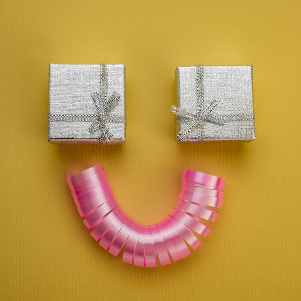 一对银色礼盒和粉红色丝带在棕色的背景。图片下载