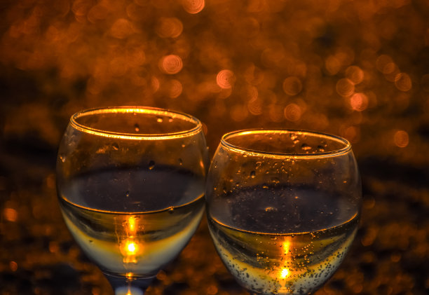 在夕阳的背景下，在海边喝一杯香槟。图片下载