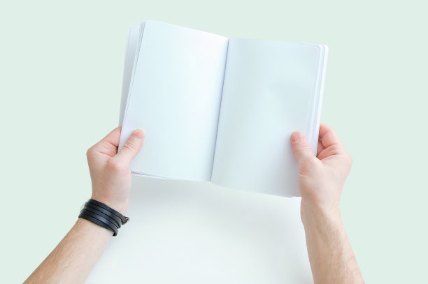 一个白人手里拿着打开的笔记本。从以上观点。白色背景。图片下载