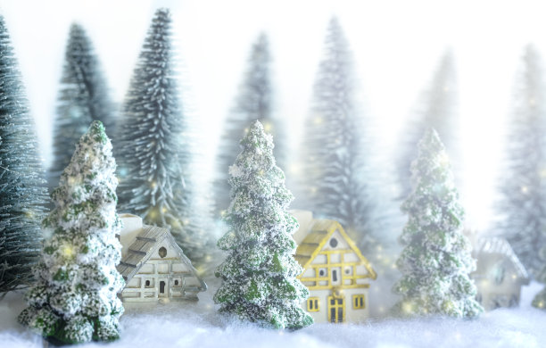 森林里有房子的迷你雪圣诞树。散景灯的背景。图片下载