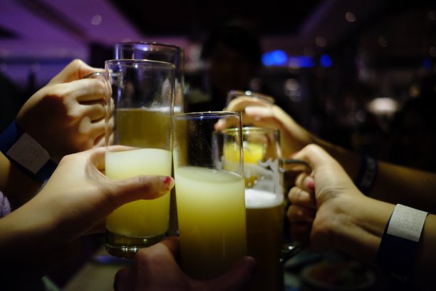 近几手举起果汁和葡萄酒酒杯，在酒吧灯光下庆祝派对。图片下载