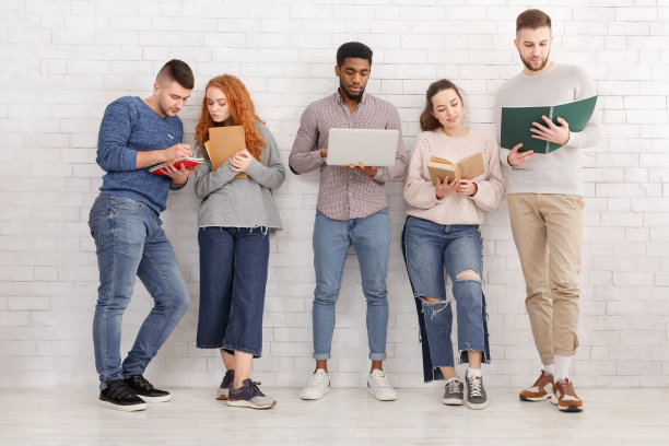 各种各样的学生靠着白墙准备考试图片下载