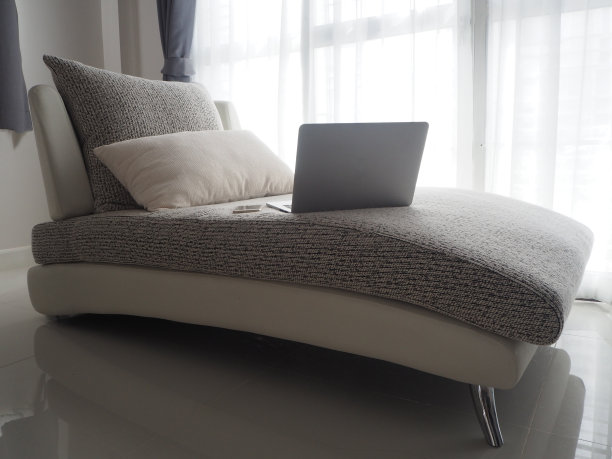 黑色笔记本电脑，白色现代沙发，白色窗帘纹理背景。图片下载