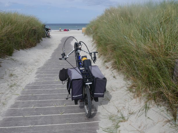 沙滩度假手自行车和轮椅。手动自行车有变速装置，电动辅助，并与轮椅夹连接。图片下载